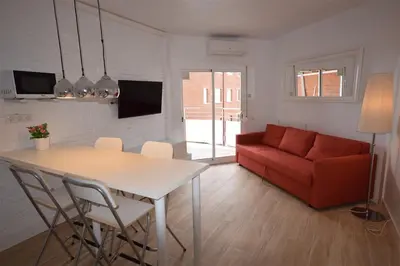 a living room with a table and a red couch at Apartamento Playa Mar in Castelldefels