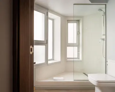 a bathroom with a shower and a toilet and windows at Hotel Madanis Liceo in Hospitalet de Llobregat