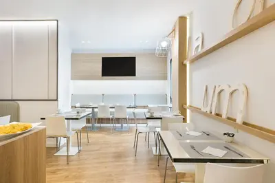 a dining room with tables and chairs and a flat screen tv at Hotel Acta Laumon in Barcelona