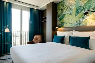 a bedroom with a large white bed with blue pillows at Motel One Barcelona-Ciutadella in Barcelona