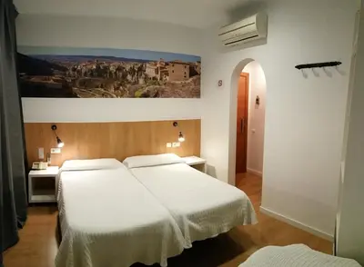 a bedroom with two beds and a painting on the wall at Hostal Restaurante Cornella in Cornellà de Llobregat