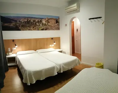 a bedroom with two beds and a painting on the wall at Hostal Restaurante Cornella in Cornellà de Llobregat