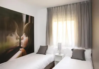 a room with two beds and a painting of a girl at MH Apartments Suites in Barcelona