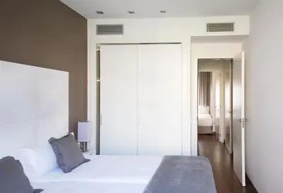 a bedroom with a large white bed and a bathroom at MH Apartments Suites in Barcelona