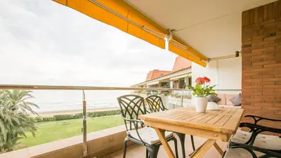 a wooden table and chairs on a balcony with a view of the ocean at GAVA 2 BEACHFRONT PENTHOUSE in Gavà