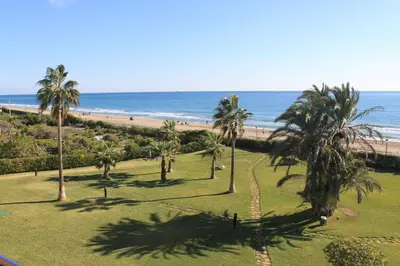 a view of a beach with palm trees and the ocean at GAVA 2 BEACHFRONT PENTHOUSE in Gavà