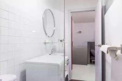 a white bathroom with a sink and a mirror at Old City Beach House in Barcelona