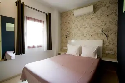 a bedroom with a bed with white sheets and a window at Old City Beach House in Barcelona