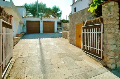 a driveway with two garage doors and a fence at Spacious Apartment in Canyelles with Private Pool in Canyelles