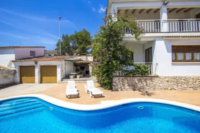 a villa with a swimming pool in front of a house at Spacious Apartment in Canyelles with Private Pool in Canyelles