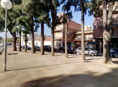a row of trees in a parking lot with cars at Casa Carmen Barcelona in El Prat de Llobregat