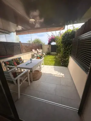a small patio with a white table and chairs at Beach flat with garden in Castelldefels