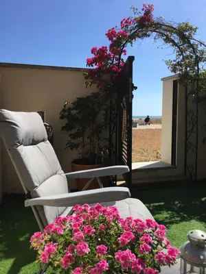 a chair and a table with flowers on a patio at Beach flat with garden in Castelldefels