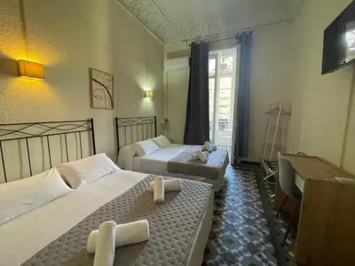 a hotel room with two beds and a desk at Hostal Balmes Centro in Barcelona