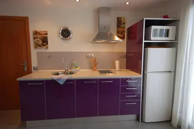 a kitchen with purple cabinets and a white refrigerator at Sitges Apartment in Sitges