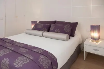 a bed with purple and white sheets and two lamps at Hostal Goya in Barcelona