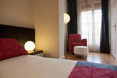 a bedroom with a bed and a red chair at Hostal Goya in Barcelona