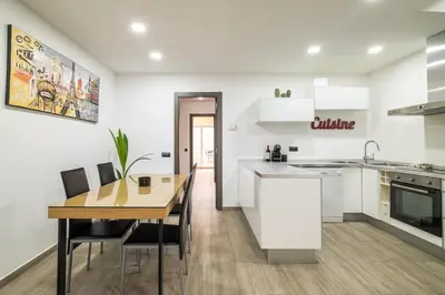 a kitchen and dining room with white cabinets and a wooden table at Luxury Beach Apartment, next to the sea in Premiá de Mar