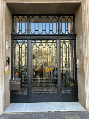 a black gate with cars in the reflection of a building at Fisa Rentals Gran Via Apartments in Barcelona