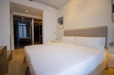 a bedroom with a large white bed and a bathroom at Storni Barcelona by Forget me not in Barcelona
