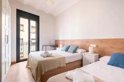 a bedroom with two beds and a balcony at Fira Barcelona Apartment in Hospitalet de Llobregat