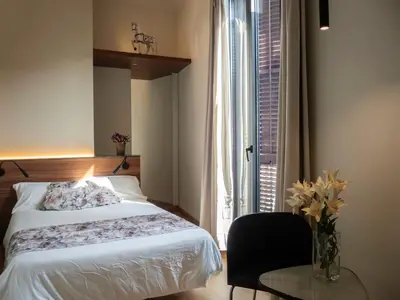 a bedroom with a bed and a table and a window at Pension Ciudadela in Barcelona