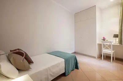 a white bedroom with a bed and a chair at BCNGOTIC 22 in Barcelona