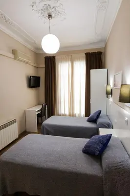 a hotel room with two beds and a window at Hostal Lesseps in Barcelona