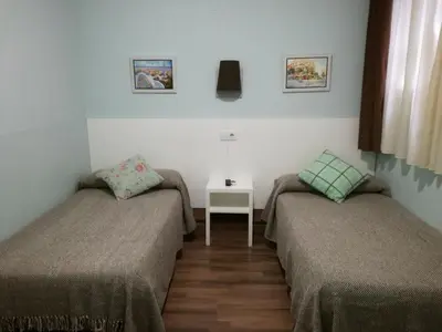 a room with two beds and a table with a lamp at Hostal Lesseps in Barcelona