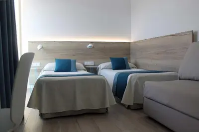 a hotel room with two beds with blue pillows at Rocatel in Canet de Mar