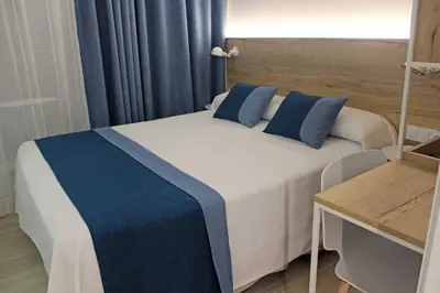 a bedroom with a large bed with blue pillows at Rocatel in Canet de Mar