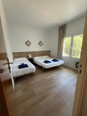 two beds in a room with wooden floors at Hostal Casa Torrent in Canet de Mar