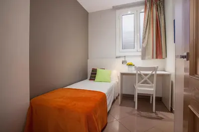 a small bedroom with a bed and a desk and a chair at BCNGOTIC43 in Barcelona