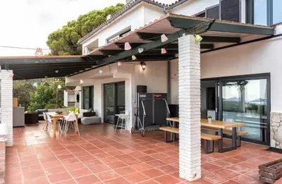 a patio with awning and tables and chairs at Villa Costa Barcelona in Arenys de Munt