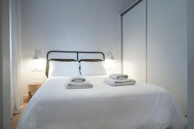 a white bed with white sheets and towels on it at Verdi Habitat Apartments in Barcelona