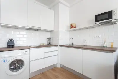 a white kitchen with a washing machine and a sink at Flateli Providencia in Barcelona