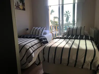 two beds in a room with a window at Beach House in Castelldefels