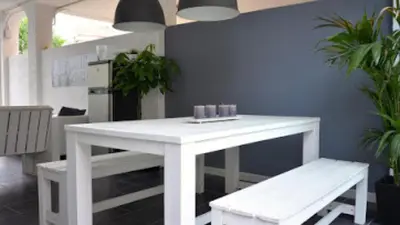a white table and bench in a room with plants at Beach House in Castelldefels