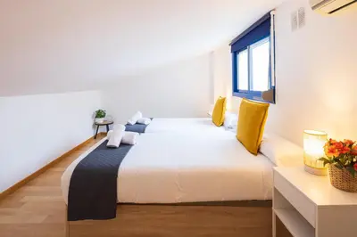 a bedroom with a large white bed with yellow pillows at Lucas House Apartments by Sitges Group in Sitges