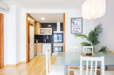 a kitchen and dining room with a glass table and white chairs at Lucas House Apartments by Sitges Group in Sitges