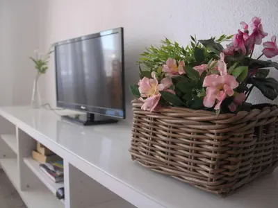 a basket of flowers on a table next to a television at VicAm Atico Duplex in Pineda de Mar