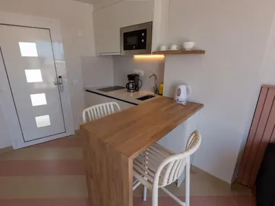 a kitchen with a wooden counter and two chairs at Apartamentos Sunway Atlanta in Sitges