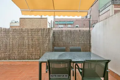 a table and chairs on a patio with a fence at Alcam Rogent in Barcelona