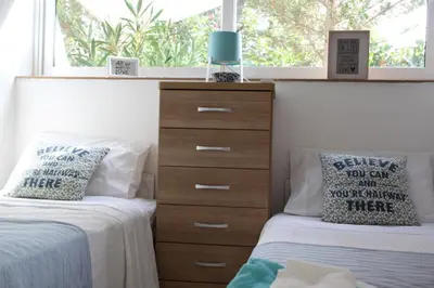 a bedroom with two beds and a dresser and a window at Villa Rosa Sitges in Can Trabal
