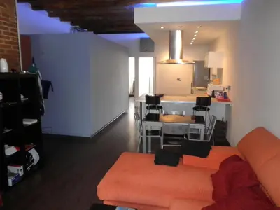 a living room with an orange couch and a kitchen at Bacrou apartment, design loft near the sea in Barcelona