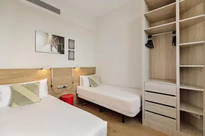 a bedroom with two beds and a book shelf at Ola Living Boqueria in Barcelona