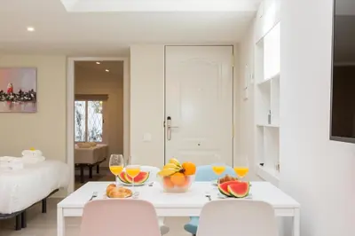 a white dining room with a table with fruit on it at Rambla de Marisol Apartments in Castelldefels