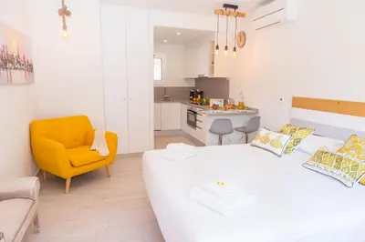 a bedroom with a white bed and a yellow chair at Rambla de Marisol Apartments in Castelldefels