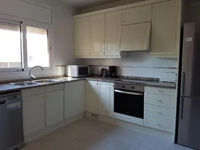 a kitchen with white cabinets and a sink and a refrigerator at Vil·la La Garriga Termal Congost in La Garriga