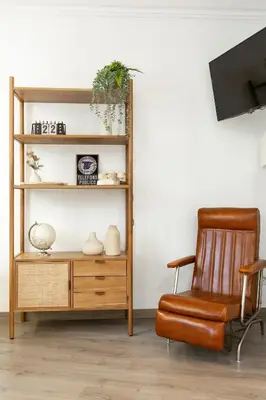 a chair sitting next to a wooden book shelf at KeyFamily Cozy Home in Barcelona